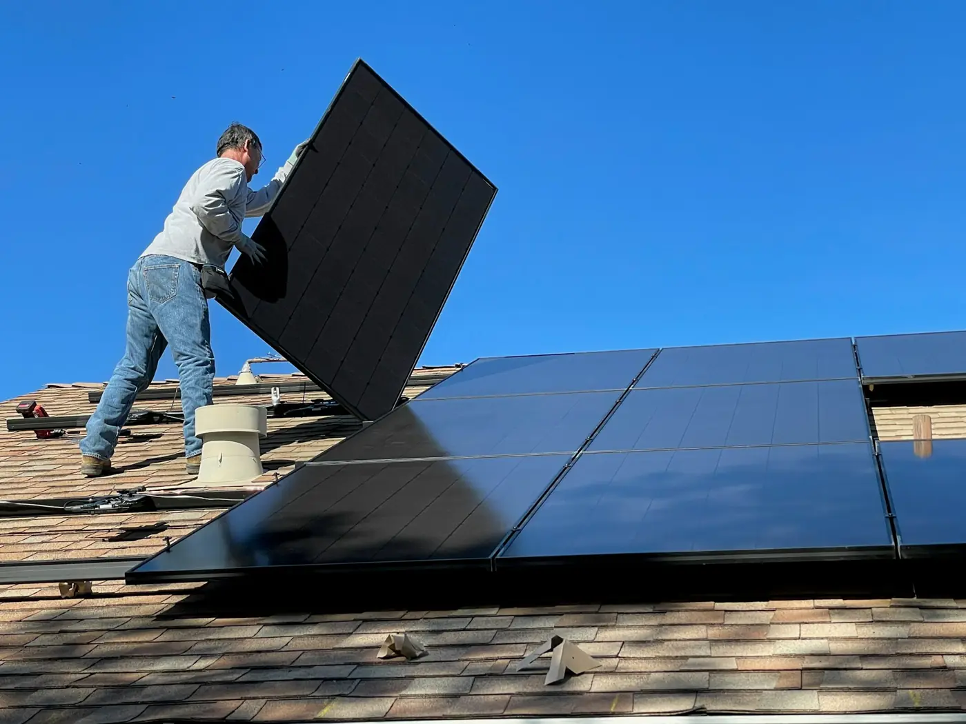 Installer carrying a solar panel across a roof